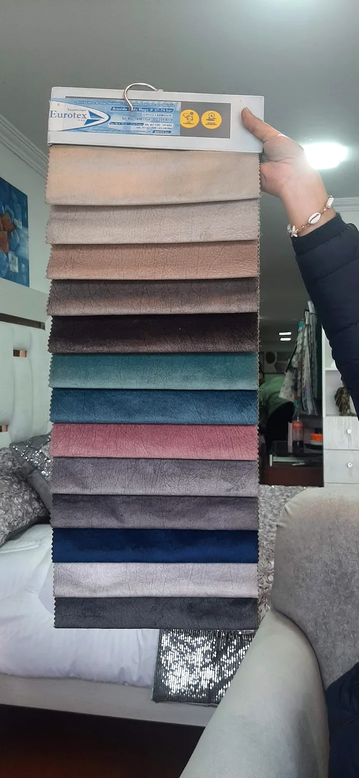 Muestrario real de telas velvet de Muebles Madeiras, sostenido en el showroom sobre una cama tapizada